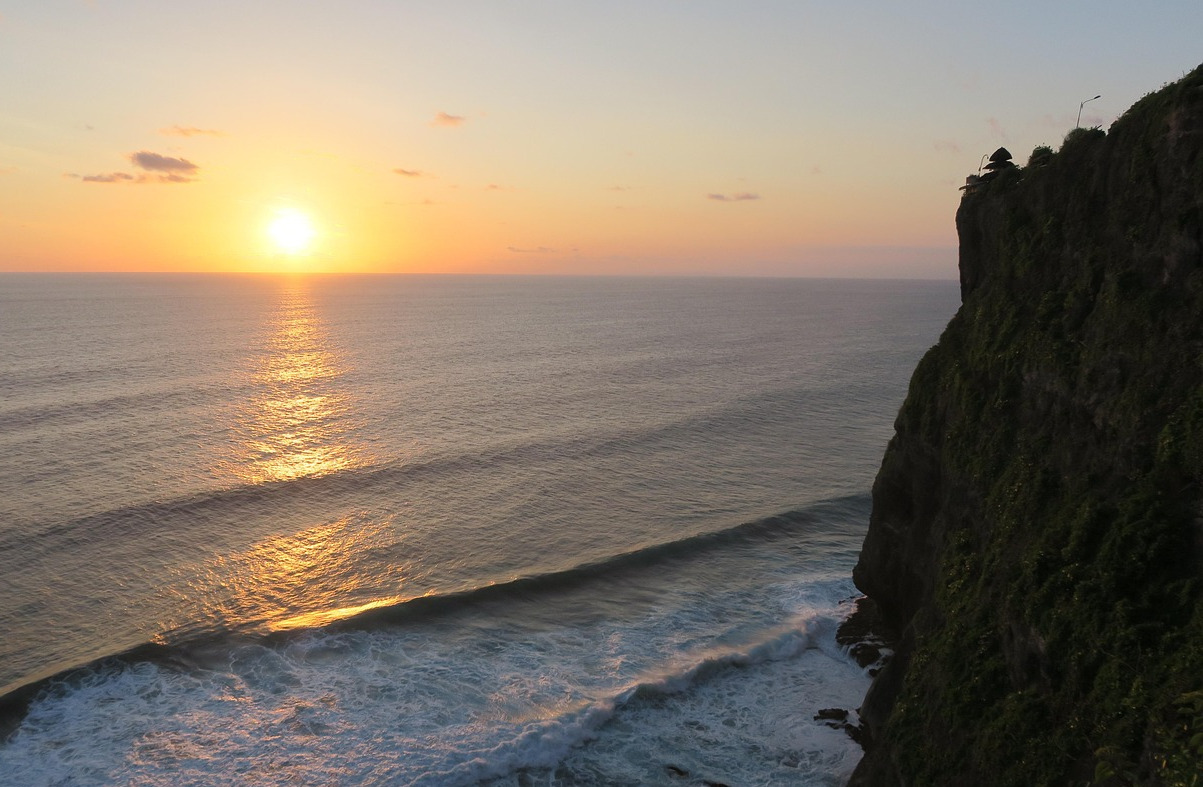 A silhouette of Uluwatu Temple with its cliffs and the soothing sunset view in Uluwatu, Bali.